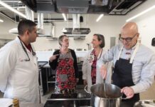Four adults talking in a commercial-style kitchen