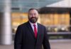 Man with beard in dark suit and red tie