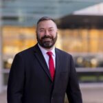 Man with beard in dark suit and red tie