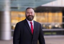 Man with beard in dark suit and red tie