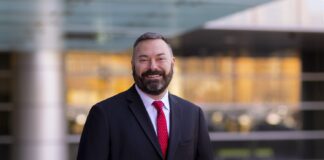 Man with beard in dark suit and red tie