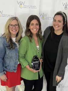 Three women together holding an award.