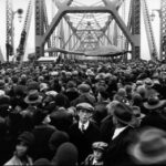 A crowd of people walking over a bridge