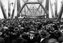 A crowd of people walking over a bridge