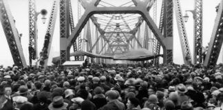 A crowd of people walking over a bridge