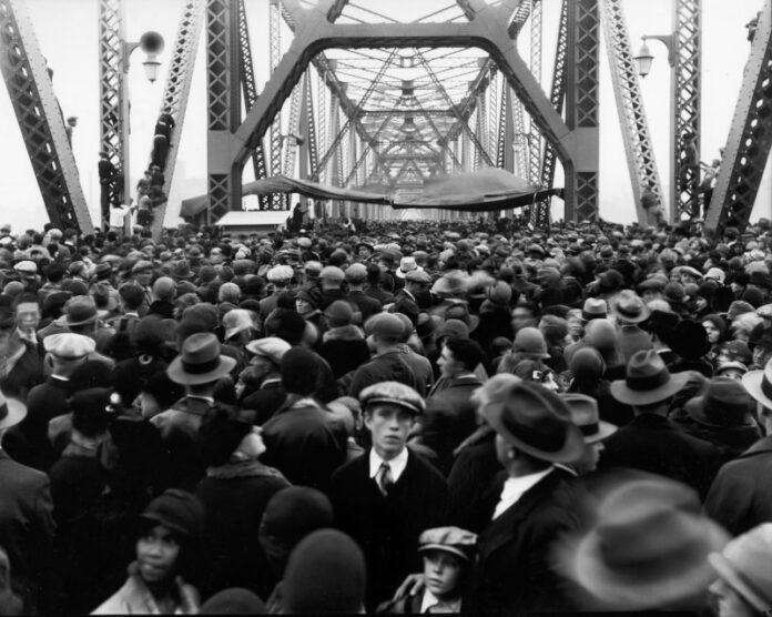 A crowd of people walking over a bridge