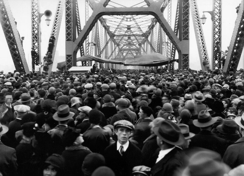 A crowd of people walking over a bridge