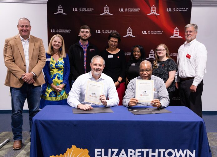 ECTC Applied Enginering_reduced size Teo men hold signed agreements with others standing behind them with an engineering school backdrop.