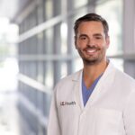 Man in white coat with UofL Health insignia
