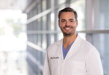 Man in white coat with UofL Health insignia