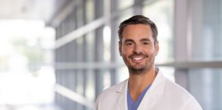 Man in white coat with UofL Health insignia