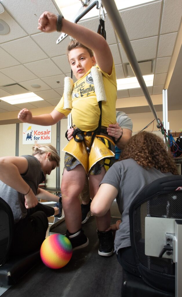 Child kicks a colorful ball while on a treadmill