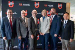 Six individuals standing in front of a UofL Health backdrop