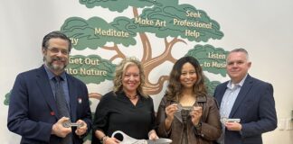 UofL Envirome Institute partners to expand youth mental health education Two men and two women with oversized scissors and ceremonial keys standing in front of a wall mural of a tree with mental health tips