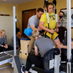 UofL researchers help paralyzed children take steps using external electrical stimulation Child on treadmill assisted by trainers