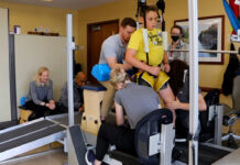 Child on treadmill assisted by trainers