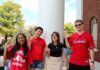 Four students on campus with "L" signs