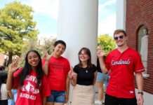 Four students on campus with "L" signs