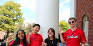 Four students on campus with "L" signs