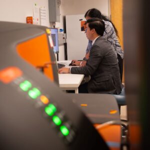 Man and woman at computer station with lighted instrument panel in foreground.