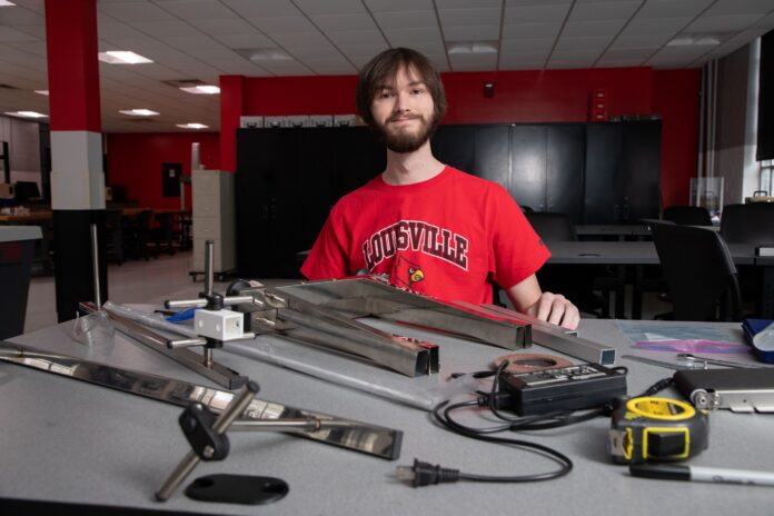 Man, smiling at worktable with assortment of metal and electrical parts