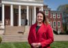 Woman in red stands in front of Grawemeyer Hall.