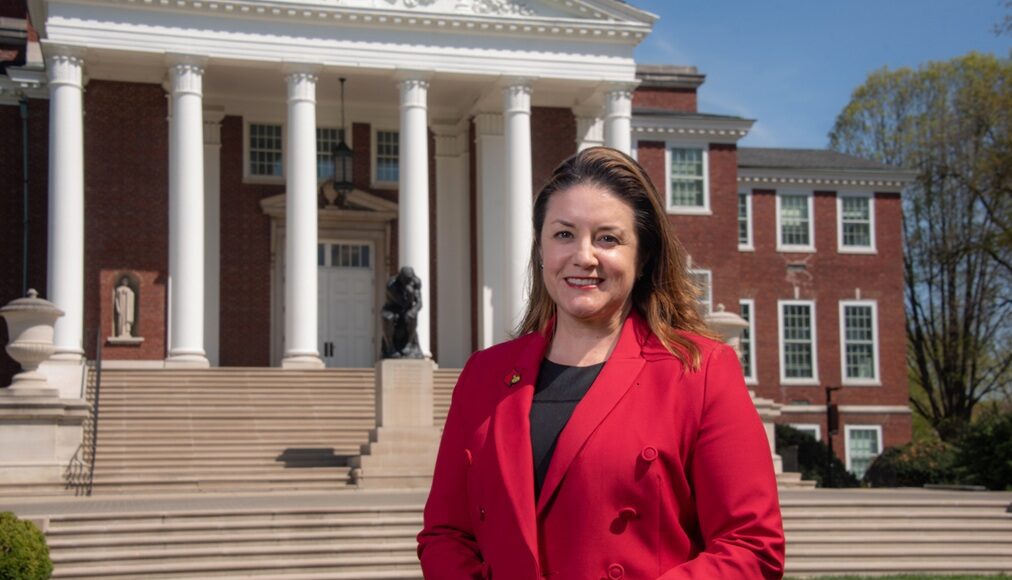 Woman in red stands in front of Grawemeyer Hall.