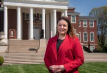 Woman in red stands in front of Grawemeyer Hall.