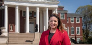 Woman in red stands in front of Grawemeyer Hall.