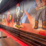 Wall decorated with Cardinal and Texas Roadhouse characters with tables and chairs