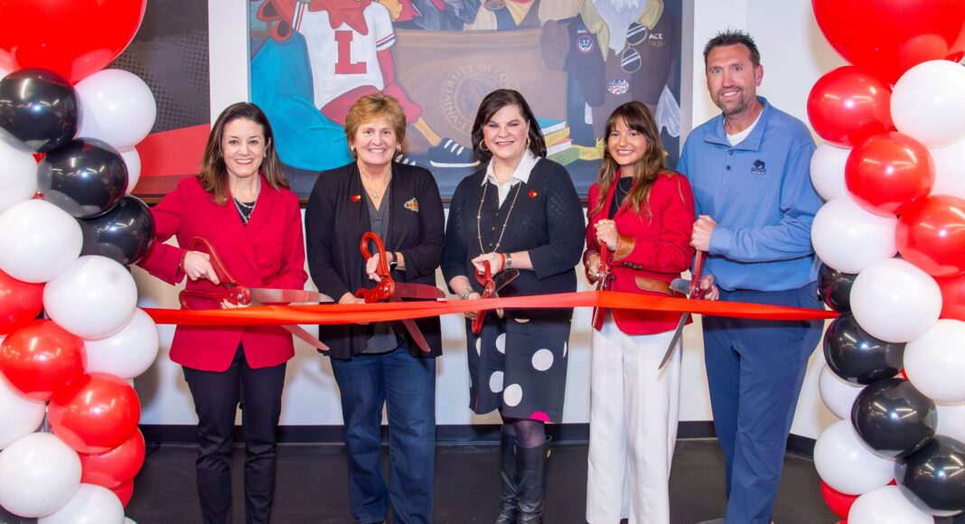 Five people with large scissors cutting a red ribbon