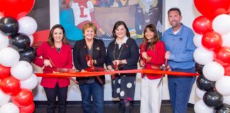 Five people with large scissors cutting a red ribbon
