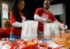 Two people assemble snack bags as part of a service project.