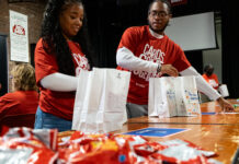 Two people assemble snack bags as part of a service project.