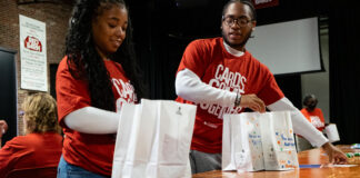 Two people assemble snack bags as part of a service project.