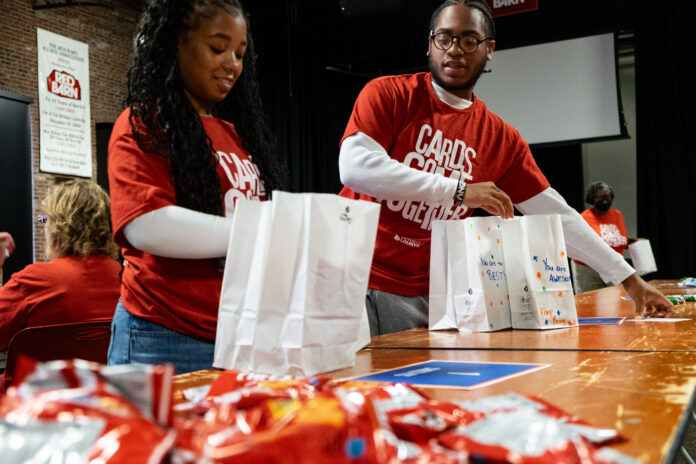 Cards Come Together-1 Two people assemble snack bags as part of a service project.