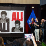 Cardinal community joins in unveiling of Muhammad Ali stamp Group clapping as the Muhammad Ali stamp is revealed.