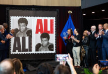 Group clapping as the Muhammad Ali stamp is revealed.
