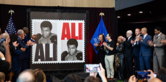 Group clapping as the Muhammad Ali stamp is revealed.