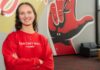 ‘We do good’ : One UofL student’s purpose in loss and raiseRED passion A smiling Carly Lasher crosses her arms in front of a UofL mural.