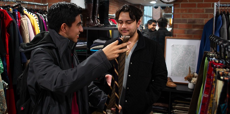 Two men look at tie choices.