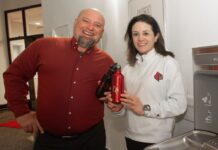 A man and woman holding water bottles next to a new water refill station