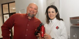 A man and woman holding water bottles next to a new water refill station