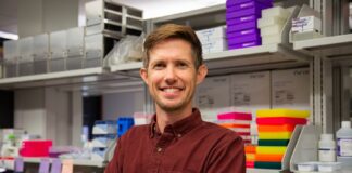Man standing in a lab with arms crossed