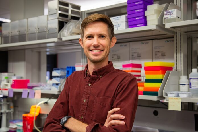 Man standing in a lab with arms crossed