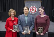 Three individuals holding award plaques