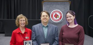 Three individuals holding award plaques