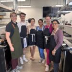 Six people standing in a commercial kitchen