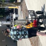 Two people and cart with scientific equipment along street.