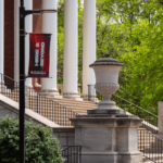 The Thinker Statue In the Springtime with a Here & Beyond Banner in the foreground